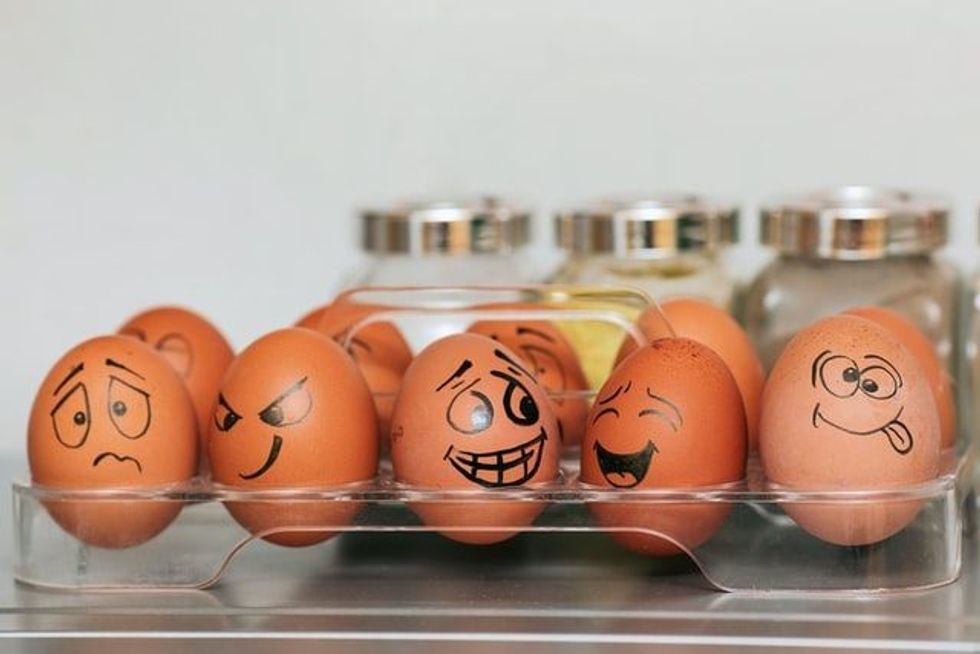 Eggs with different emojis arranged in an egg crate.