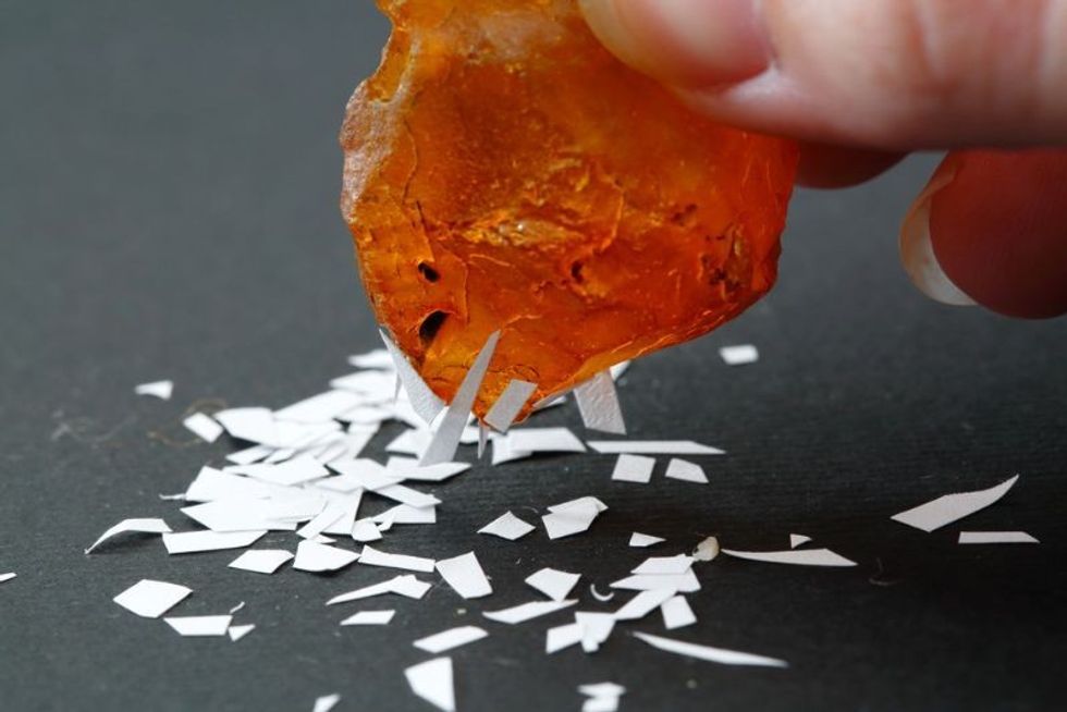 electrified piece of amber attracts pieces of paper