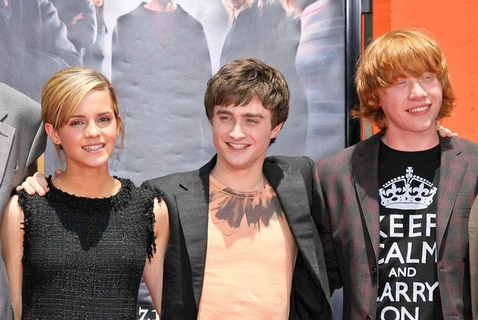 Emma Watson, Daniel Radcliffe and Rupert Grint, smiling at an event.