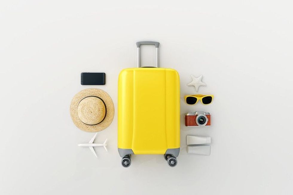 Equipment for travel arranged; a camera, sun shades,  a hat, a cellphone and a travelling bag.