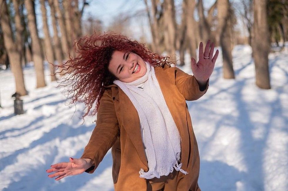 Fat woman dancing on a walk in the park in winter. 