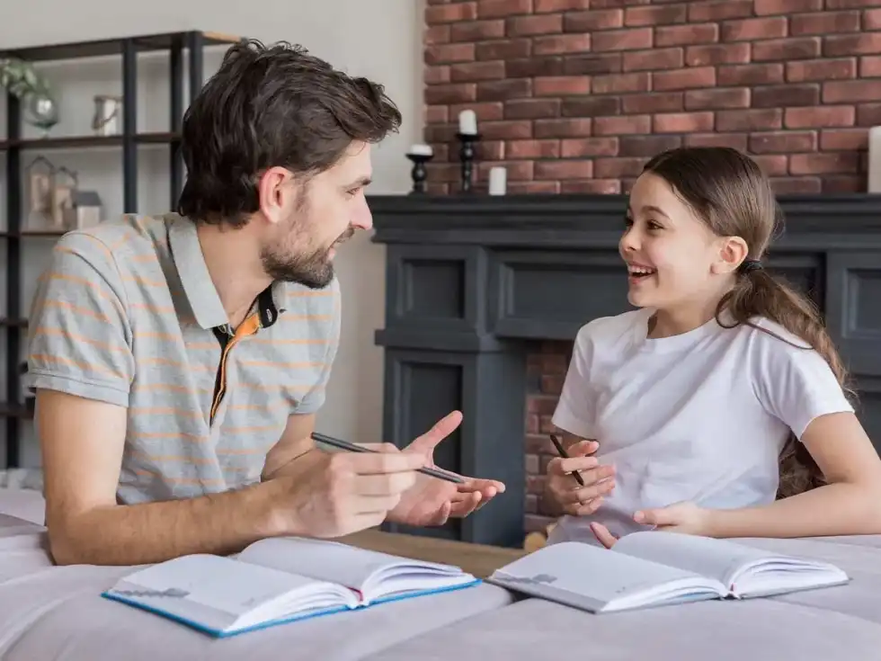 Father and daughter sat together at the table whilst he explains rounding to her.