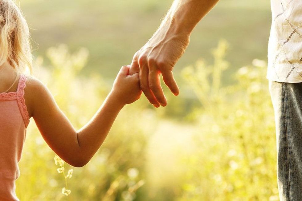 Father holding the hand of his young daughter.
