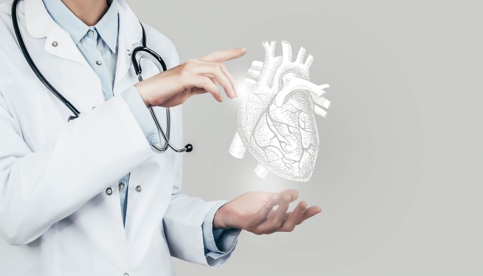 Female doctor holding virtual volumetric drawing of Heart in hand. 