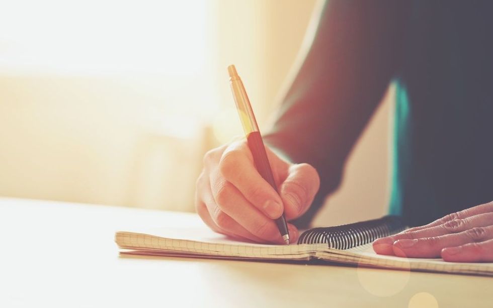 Female hands with pen writing on notebook.