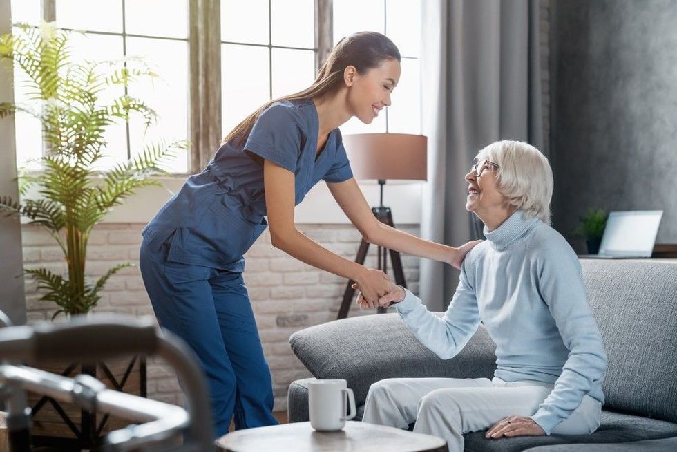 Female professional caregiver taking care of elderly woman at home