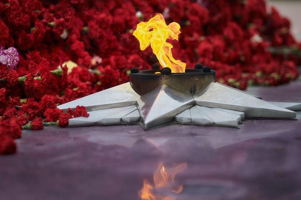 Fire ignited in a grey metal star with carnations of flowers in the background