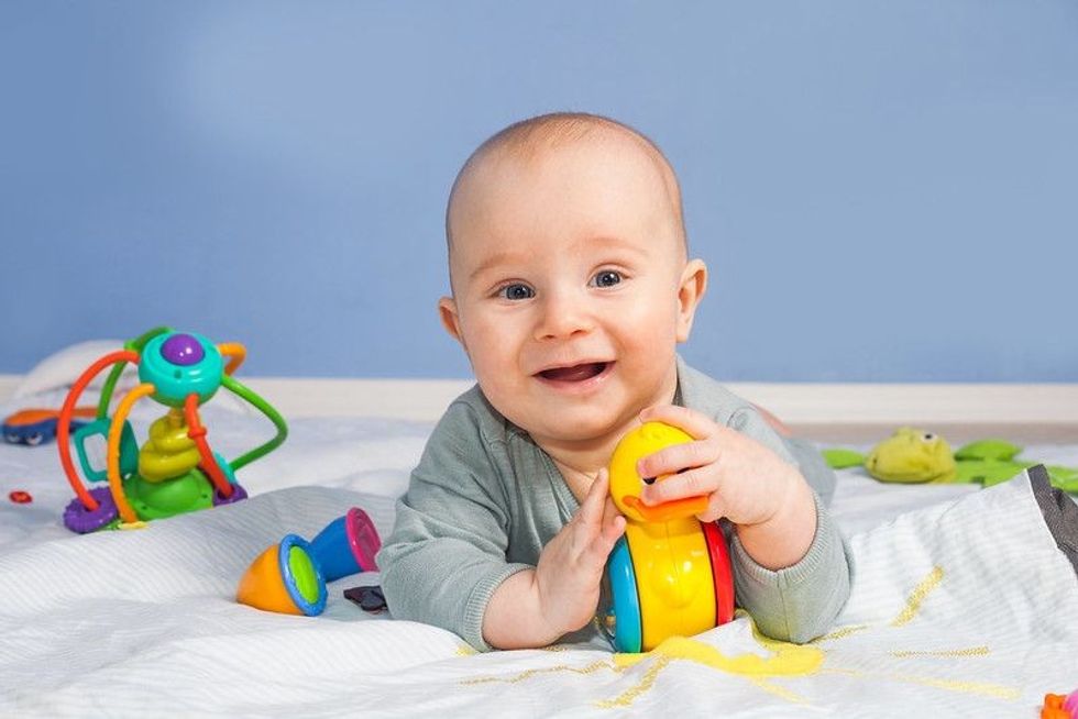 Five month old smiling baby with toys
