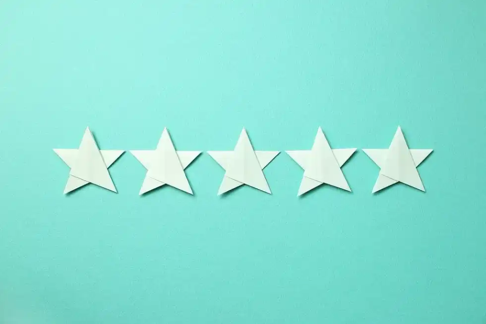 Five white origami stars against a green background.