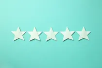 Five white origami stars against a green background.