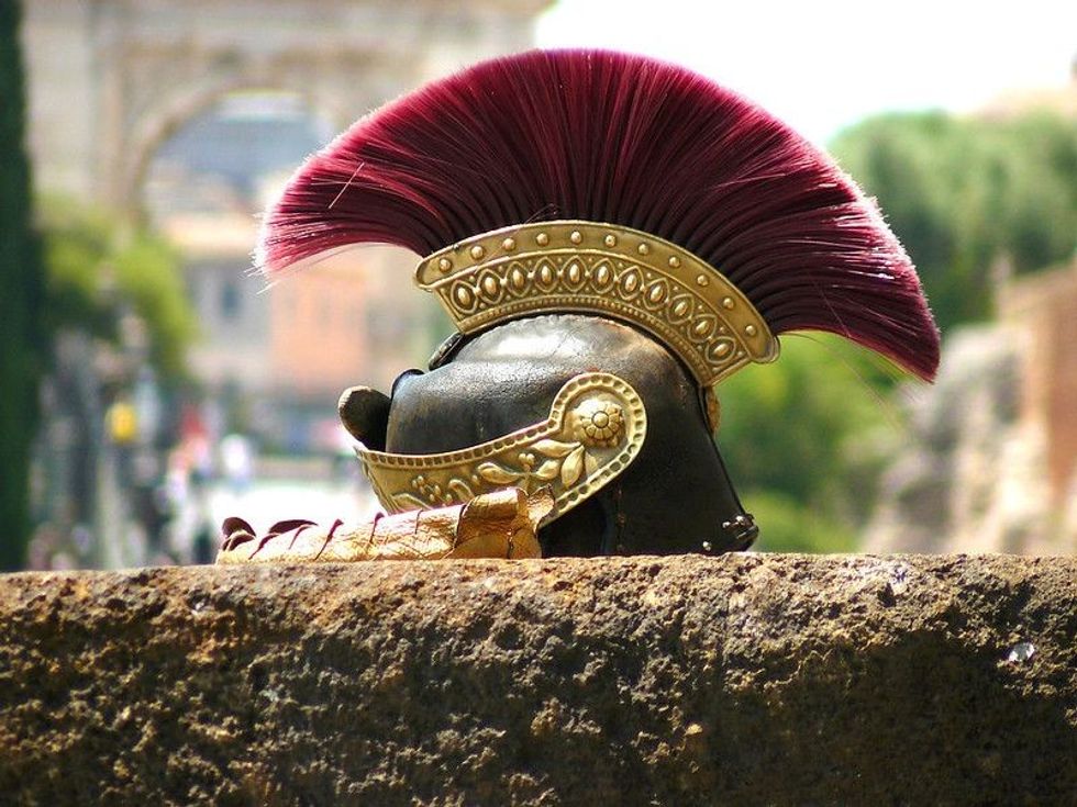 Focused Roman helmet placed on rock wall.