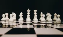 Full set of white chess pieces on a chess board.
