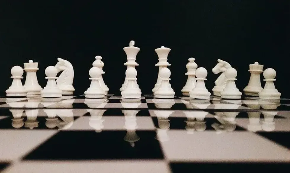 Full set of white chess pieces on a chess board.