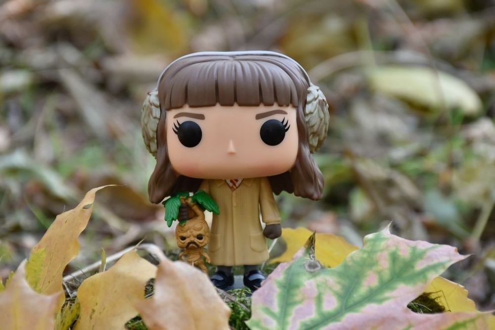 Funko Pop action figure of Hermione Granger with mandrake from movie Harry Potter.