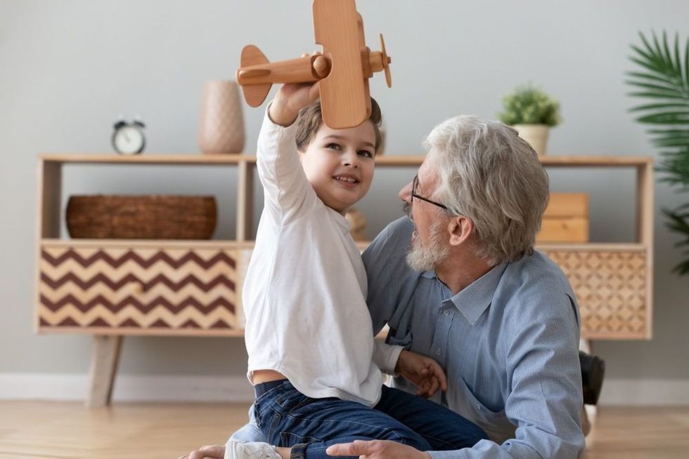 Funny small grandkid having fun with grandpa at home.