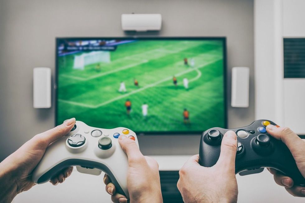 Gamer playing FIFA on TV with joysticks.