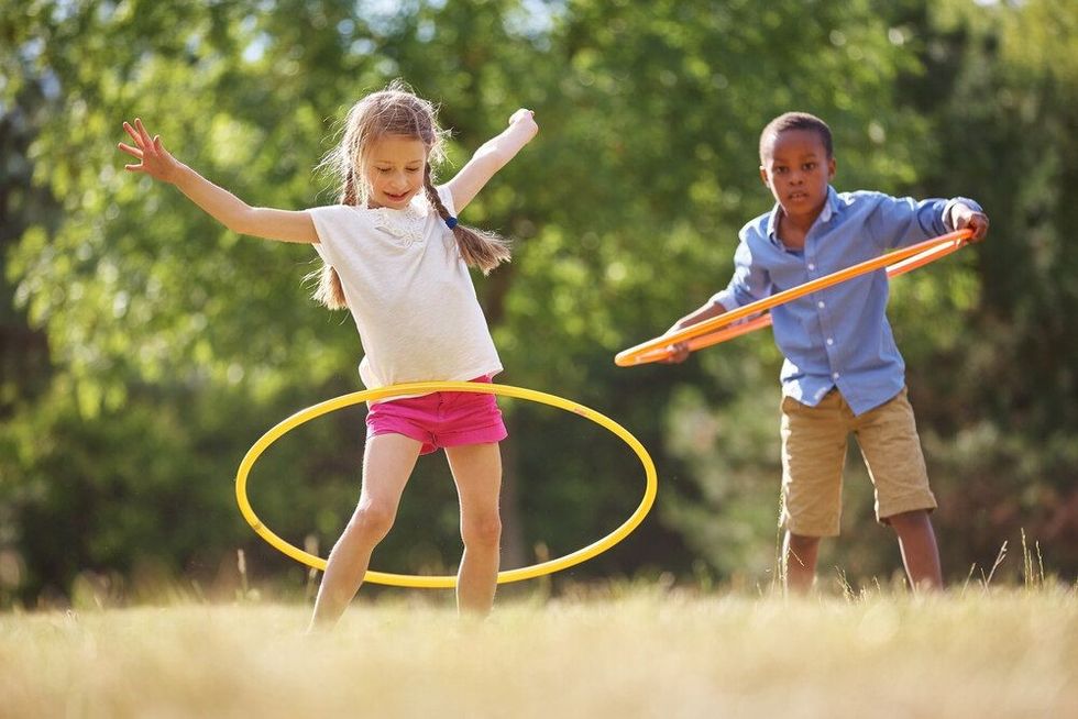 Girl and boy with hula hoop playing at the park