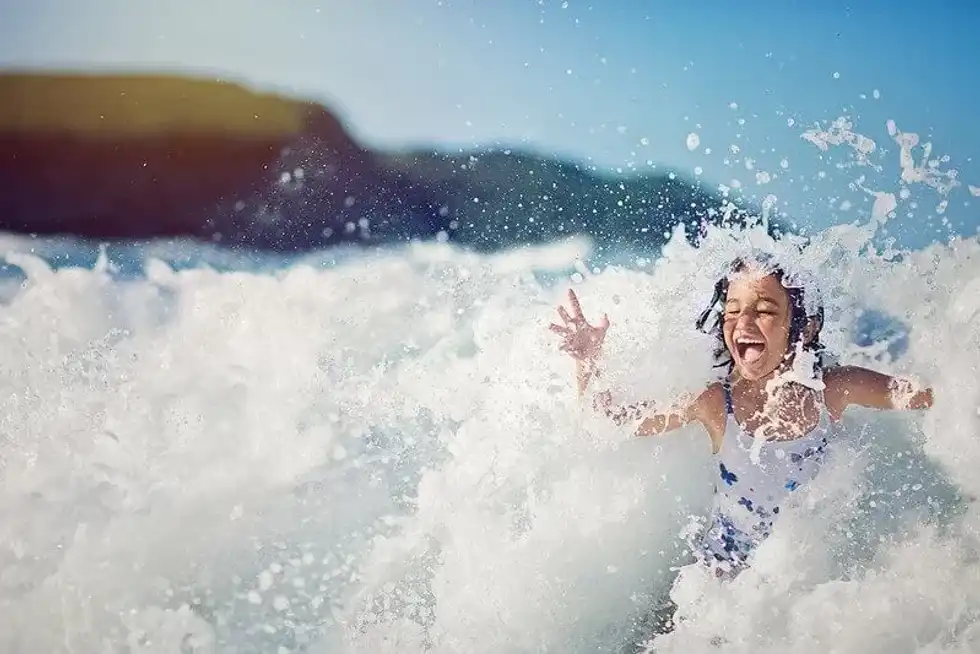 Girl enjoying being splashed in the ocean