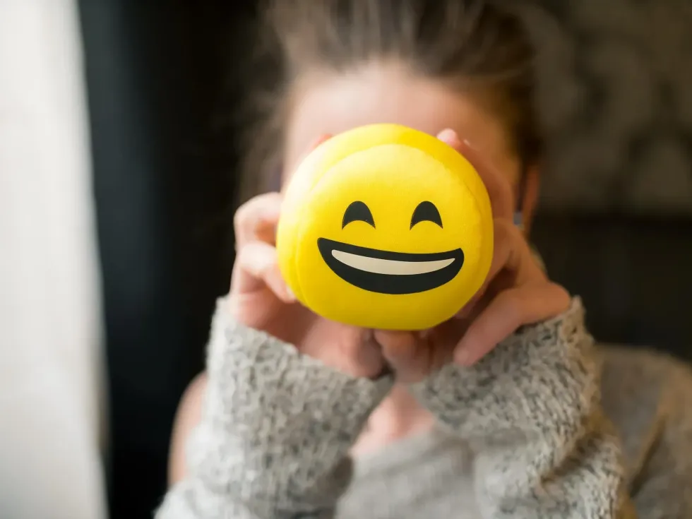 Girl holding a smiley face toy up to her face