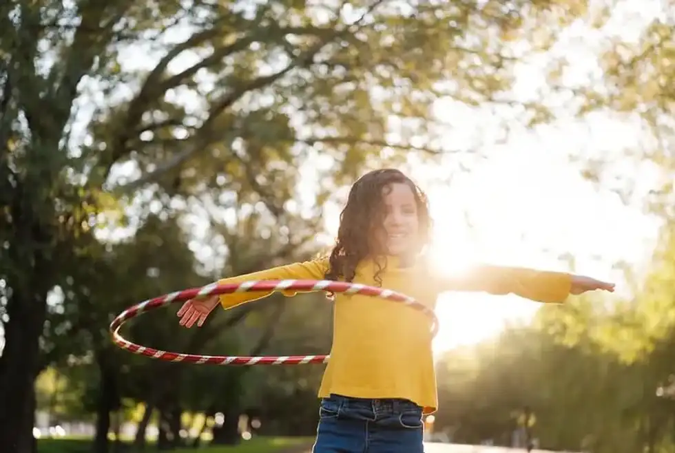 Girl learning how to hula hoop in her garden.