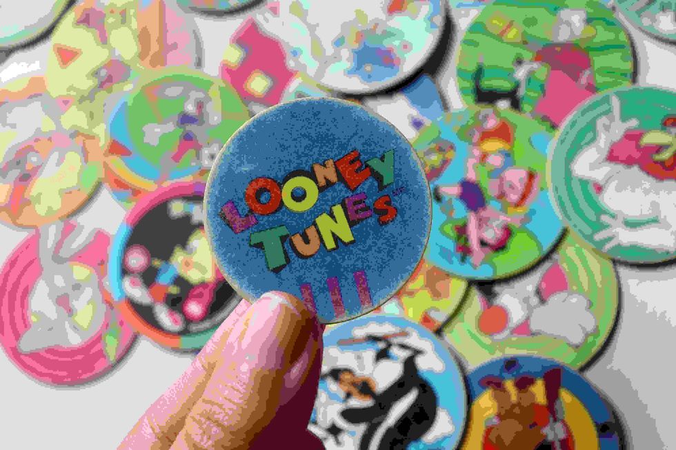  Girl's hand holding Looney Tunes tazo.