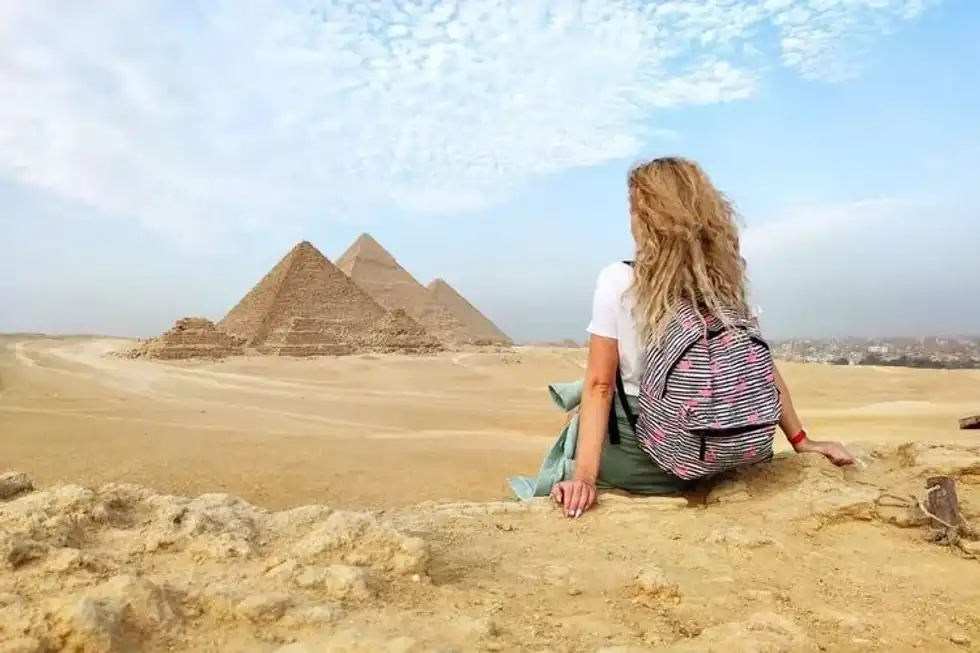 Girl sitting on a rock with a view of Pyramids of Giza