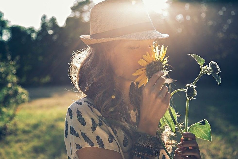 Girl smells sunflower in a sunny day.