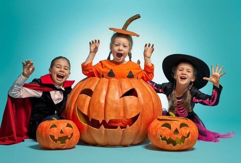 Girls posing with pumpkins wearing Halloween costumes