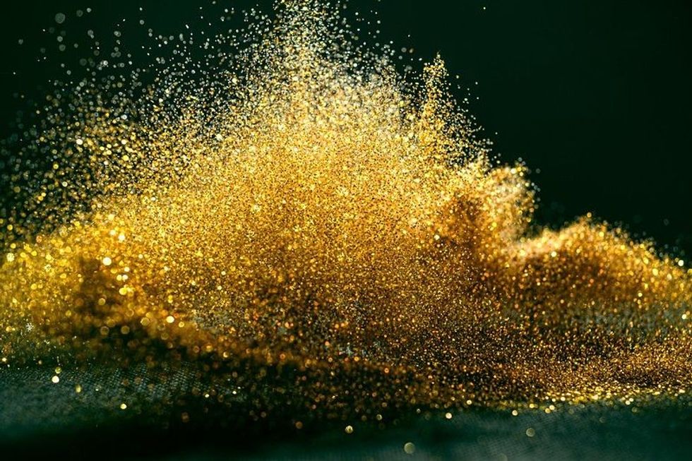Gold glitter spilled on black background
