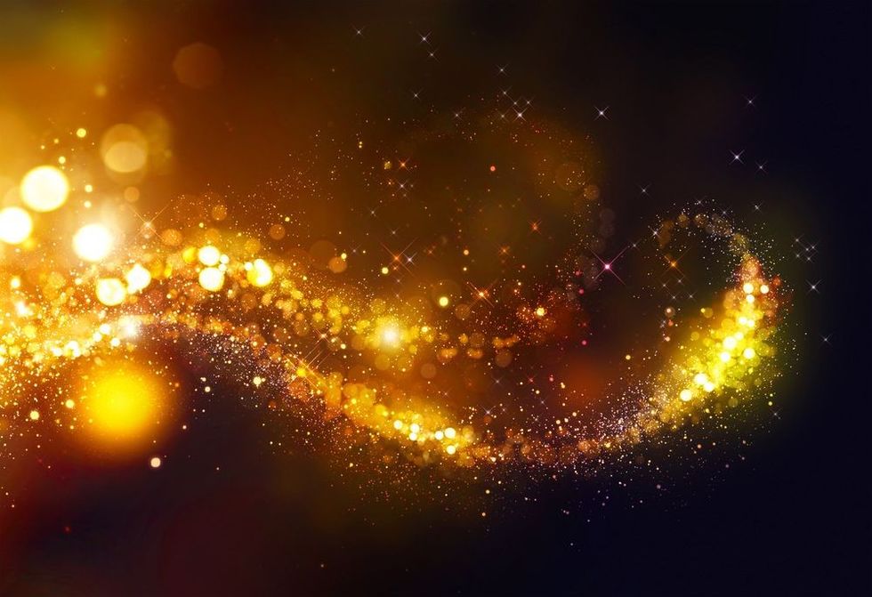Golden Christmas and New Year glittering stars swirl on black bokeh background.