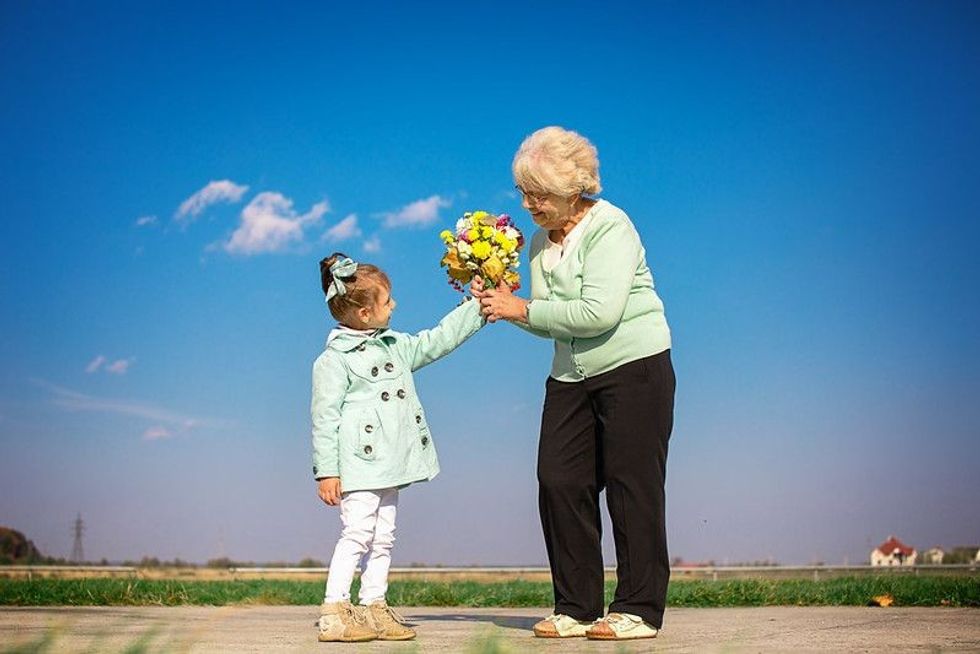 Granddaughter giving flowers to grandmother