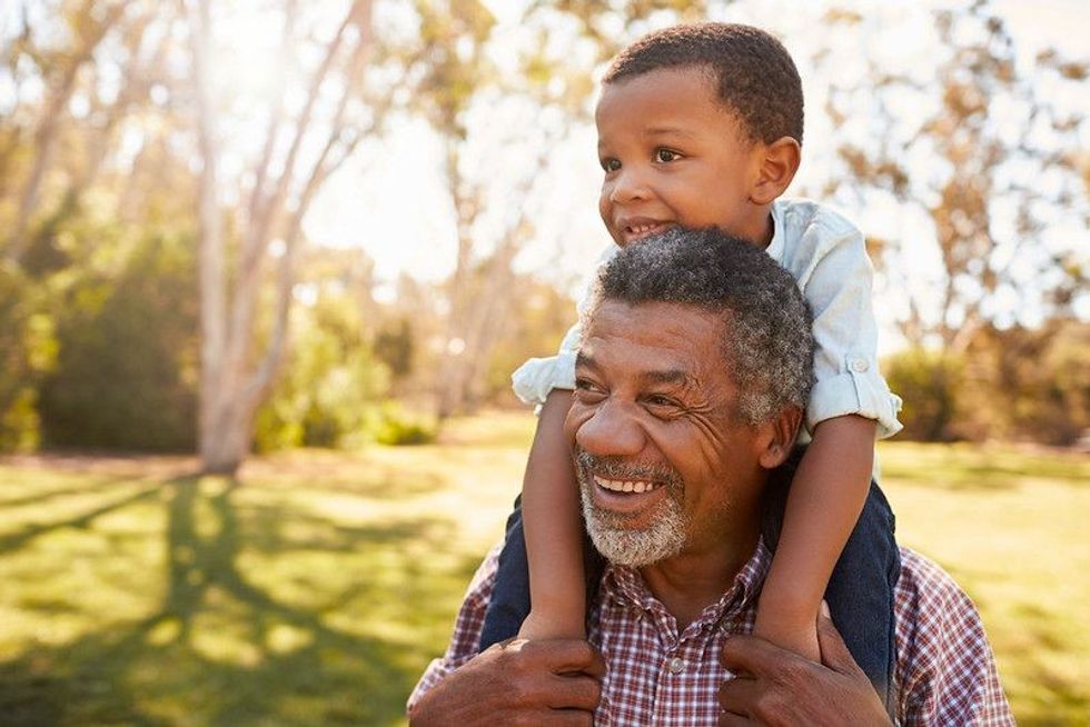 Grandfather carrying grandson on shoulders in park