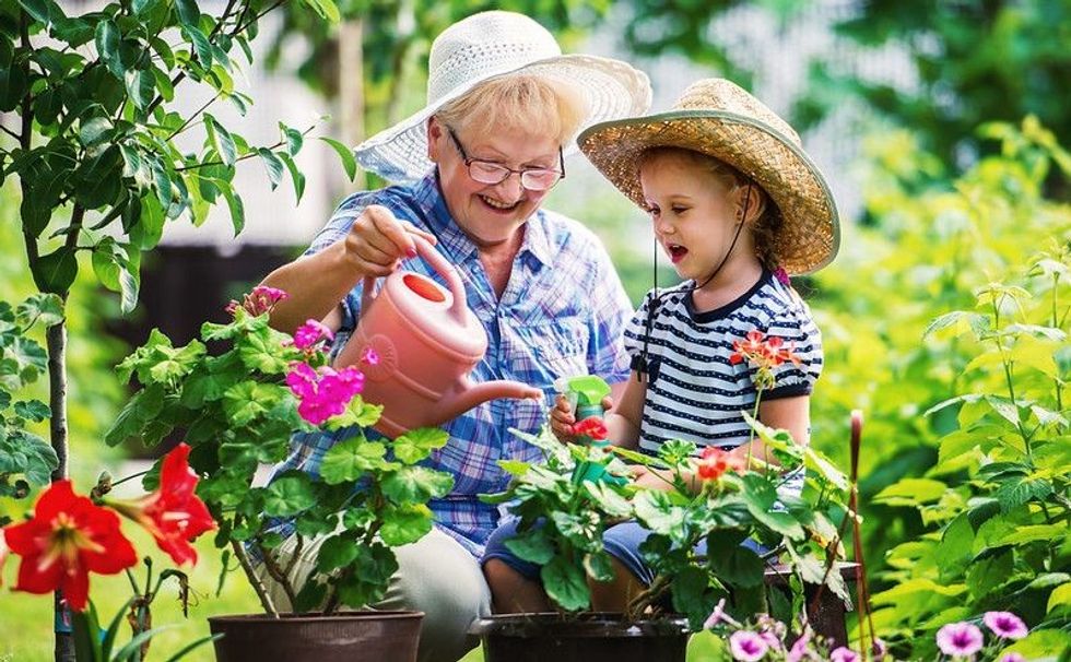 Grandmother and her grandchild enjoying in the garden with flowers