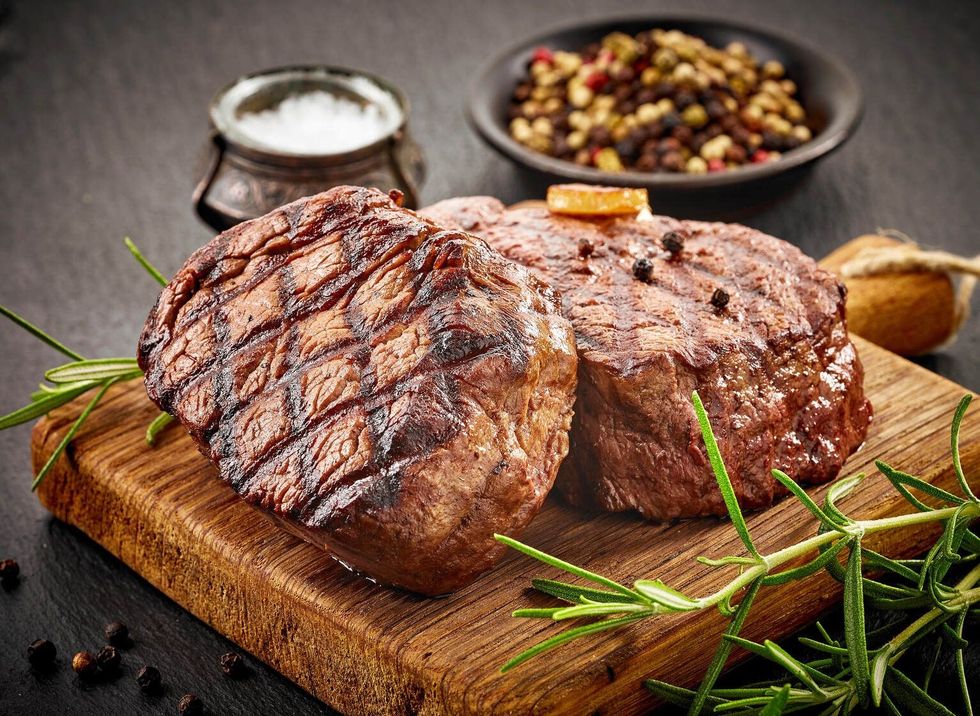 Grilled beef steaks with spices on wooden cutting board