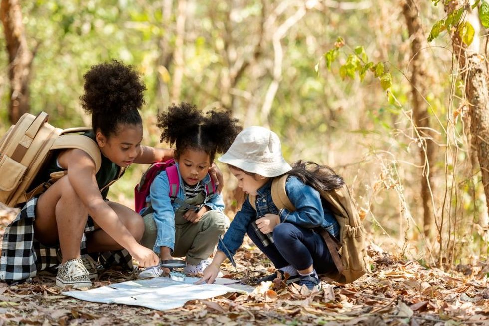 Group family children checking map for explore and find directions in the camping