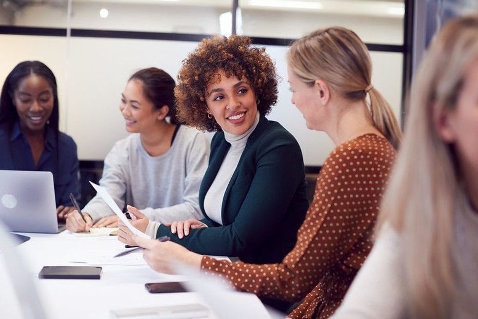 Group Of American Businesswomen collaborating in a meeting around table.