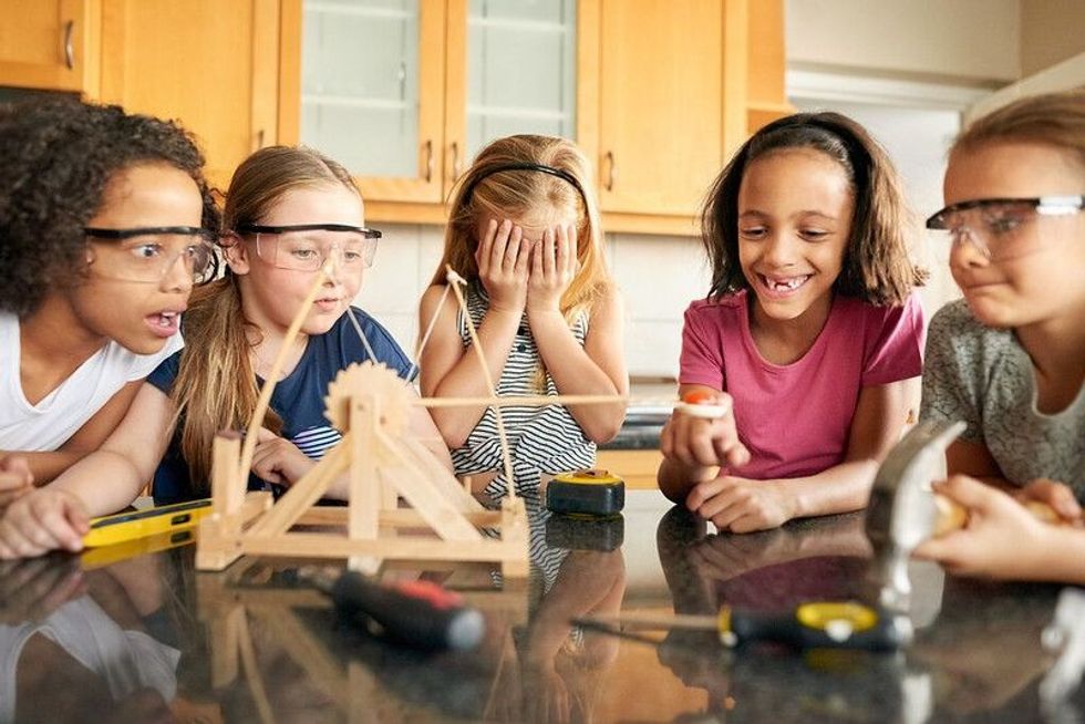 Group of little girls playing with a catapult at home