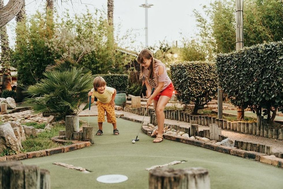 Group of two funny kids playing mini golf