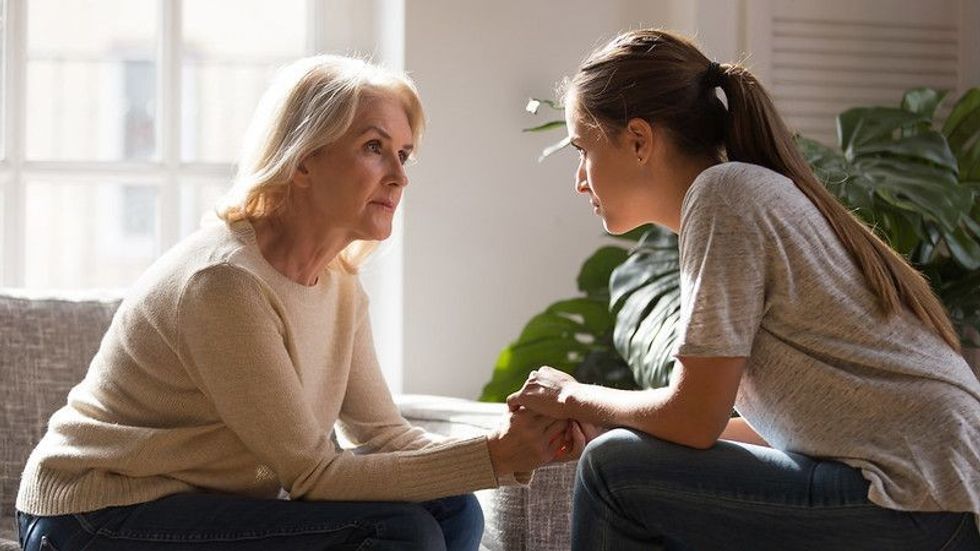 Grown up daughter holding hands of middle aged mother relatives female sitting look at each other having heart-to-heart talk, understanding support care and love of diverse generations women concept