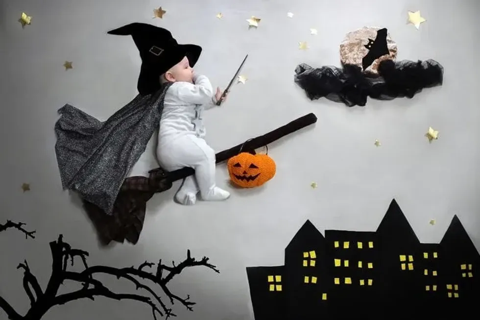 Halloween party baby on broom in wizard hat, magic wand flying to the moon with bat over night city flat lay