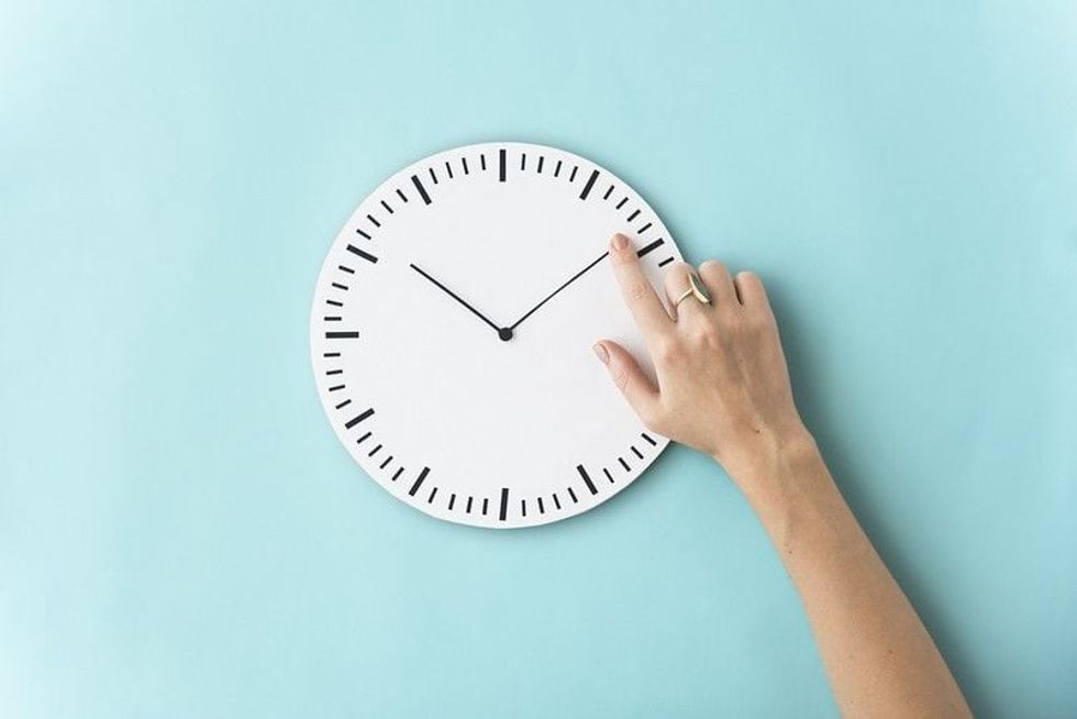Hand adjusting the minute hand on a clock.