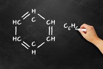 Hand drawing chemical structure and formula of benzene on a black board
