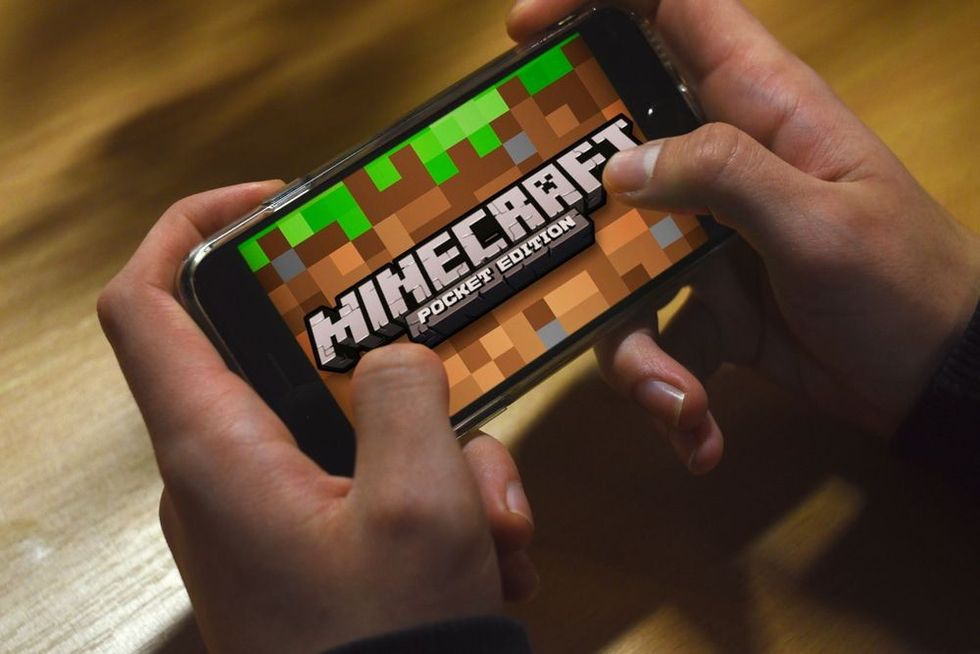Hand holding phone with Minecraft Pocket Edition logo