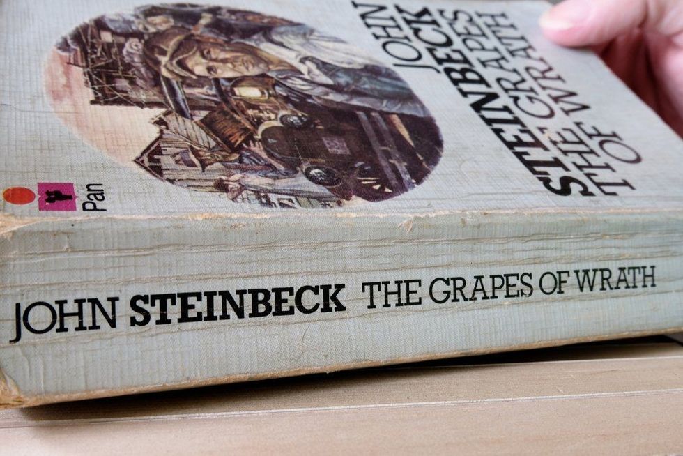 Hand opening the book by John Steinbeck