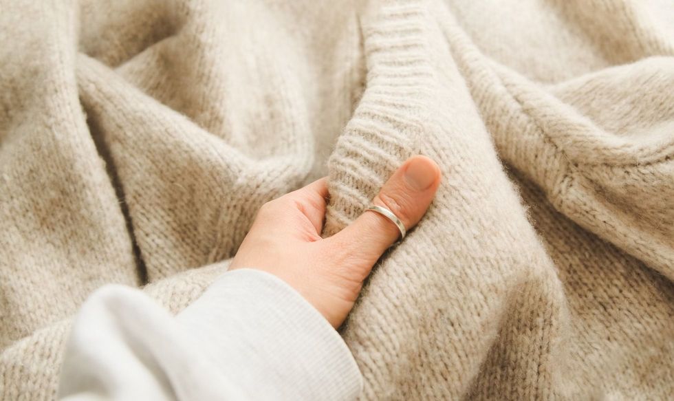 Hand touching knitted wool cloth or warm fluffy sweater