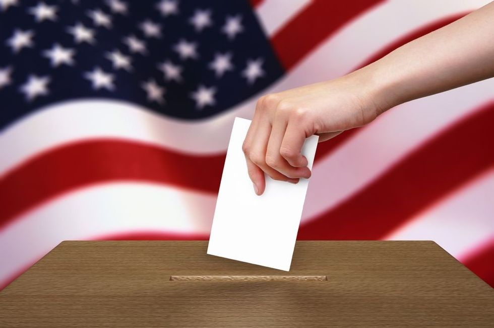 Hand with ballot and wooden box on Flag