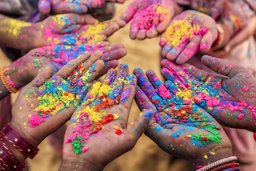 Hands coming together, covered in vibrant colors of powder, celebrating Holi, the festival that heralds the spring season.