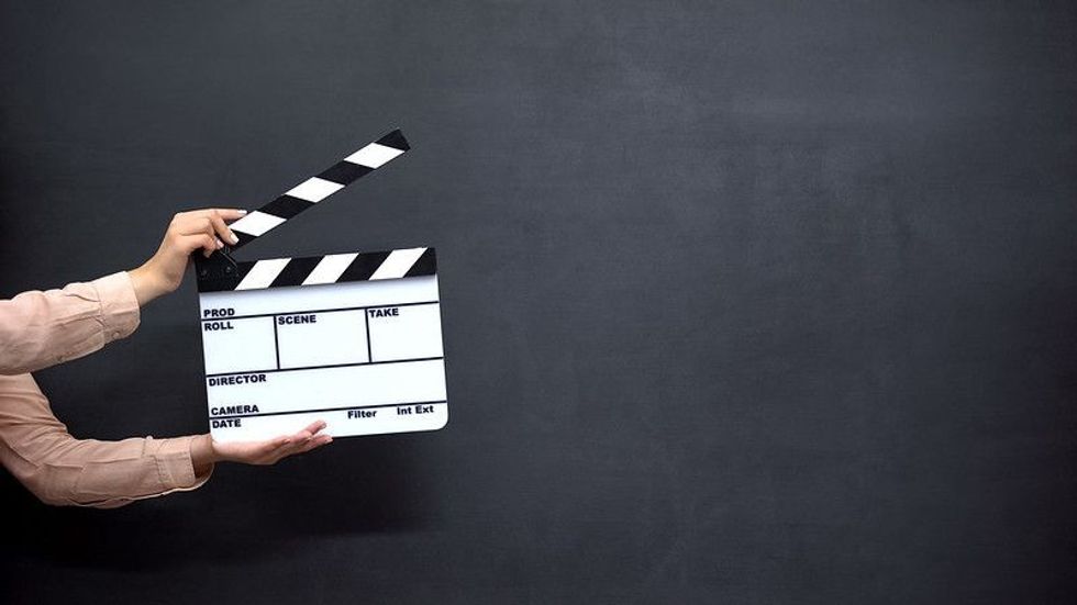 Hands holding a clapperboard against a black background.
