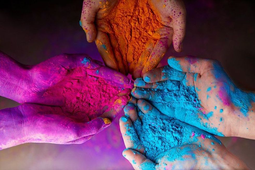 Hands holding colorful Holi powder while celebrating Indian Holi festival.