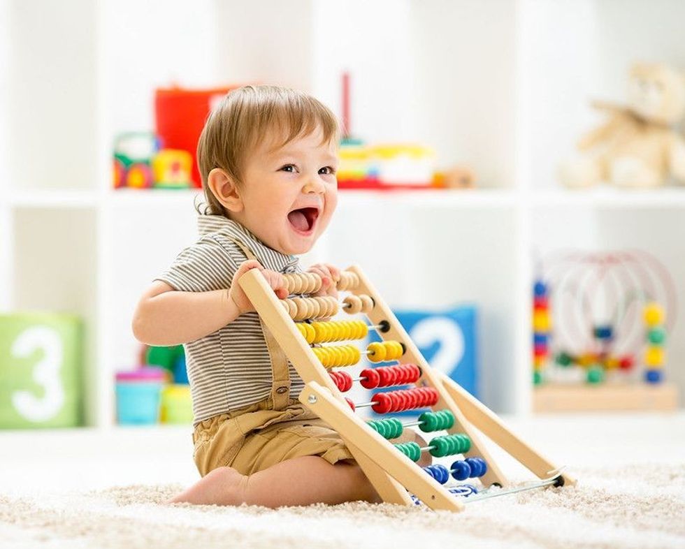 Happy baby boy playing with toy abacus